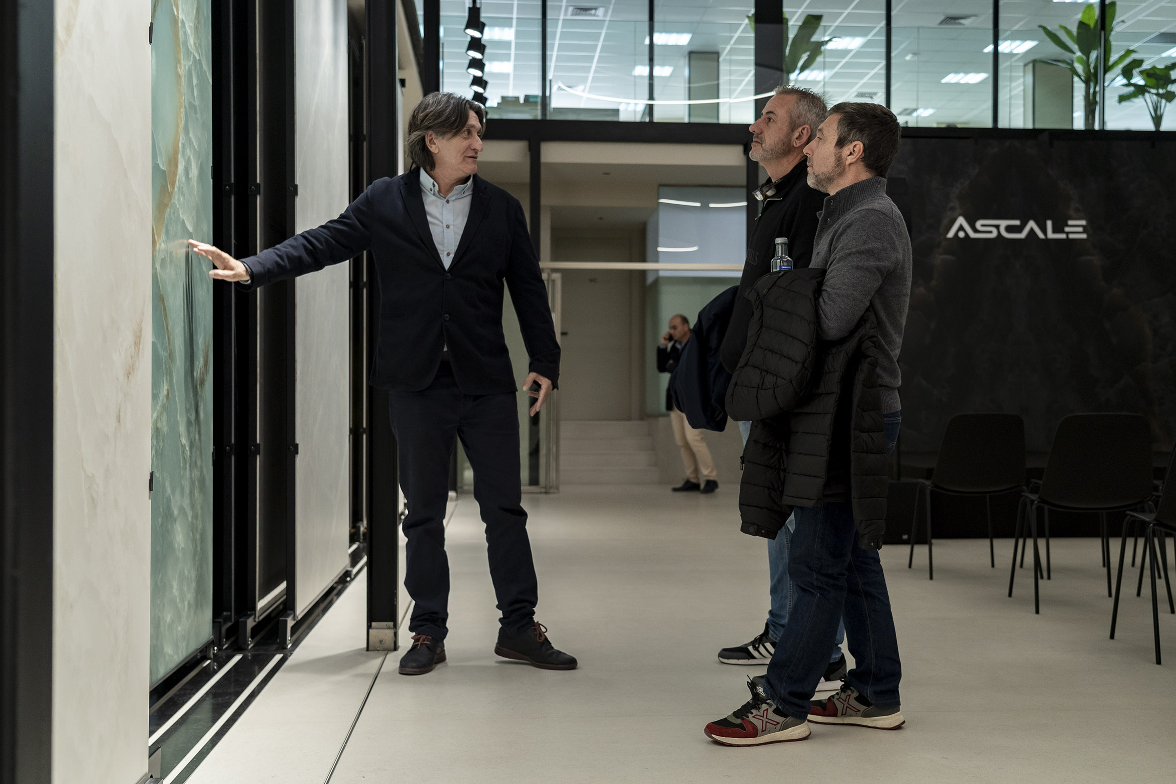 Tres personas observando de cerca una piedra sinterizada de la marca Ascale durante la charla de Rhinostone